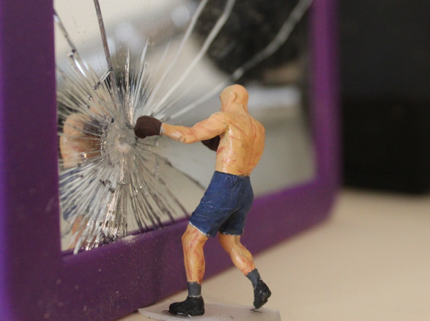 A boxer bashes his reflection in a mirror with his fist